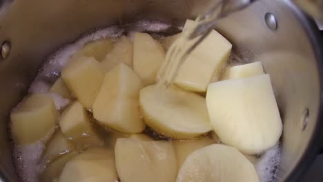 boiling water being poured on sliced potatoes cooking in a pan