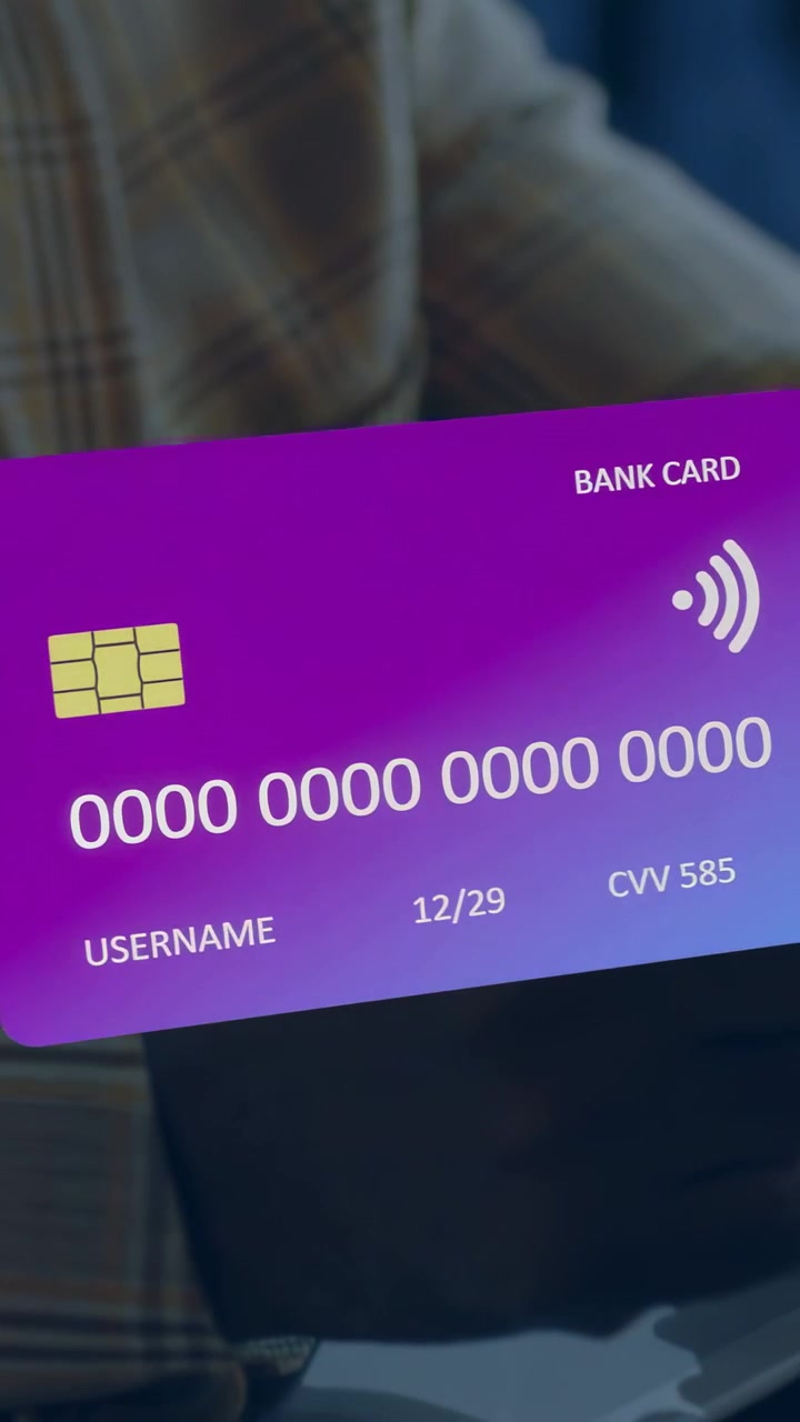 Vertical video: Man tapping phone at desk causing purple card sliding face to laptop for payment