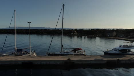 a circuling shot of a sailng boat docked on a stone pier