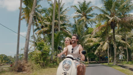 travel couple riding scooter on tropical island happy woman celebrating with arms raised enjoying fun vacation road trip with boyfriend on motorcycle ride