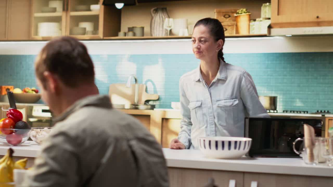 Woman pouring orange juice in glasses at the breakfast table