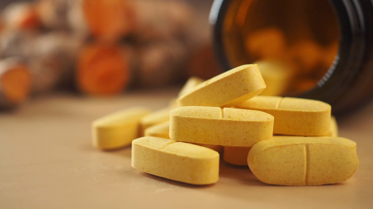 Yellow Turmeric Supplement Pills Spilled from a Bottle