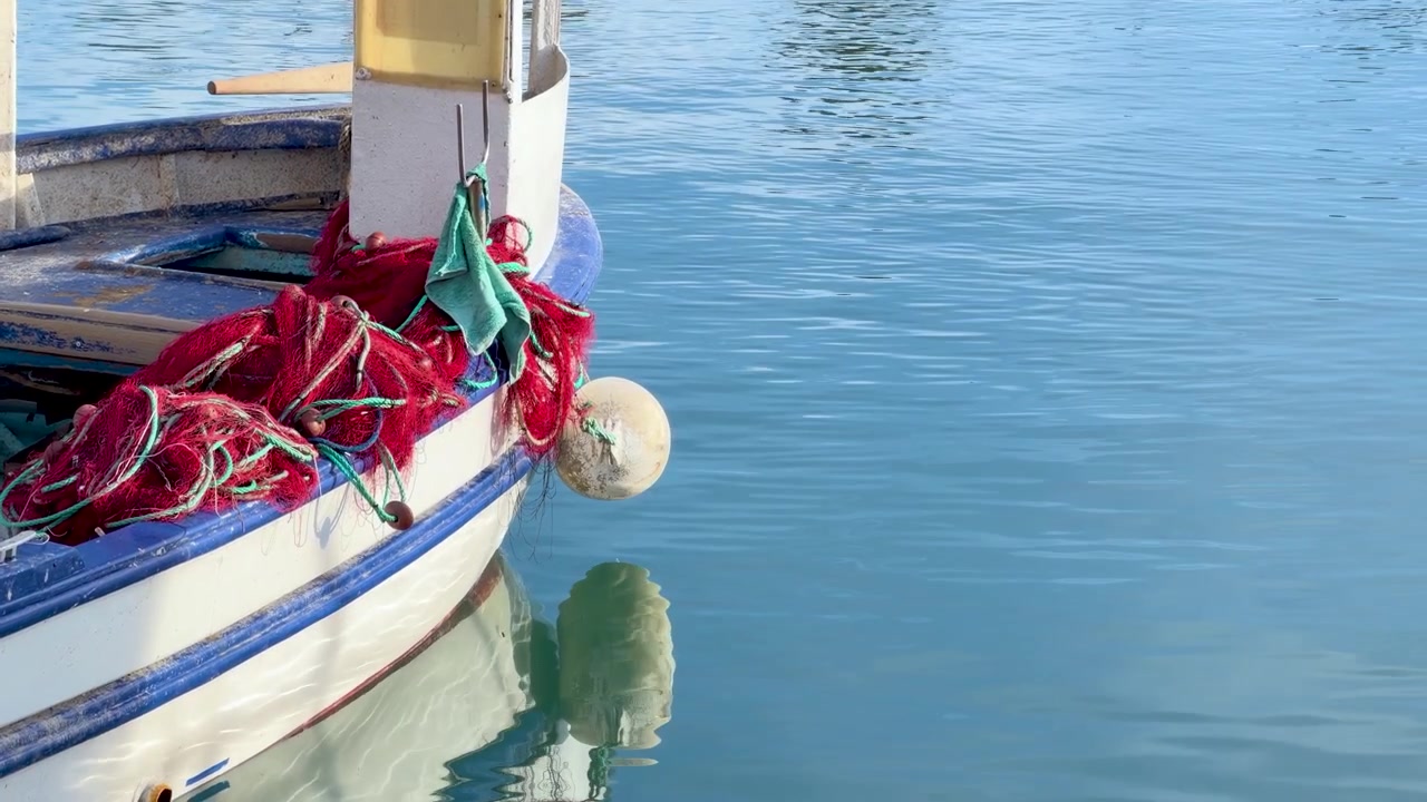 Barca da pesca con reti rosse che galleggia su acqua calma.