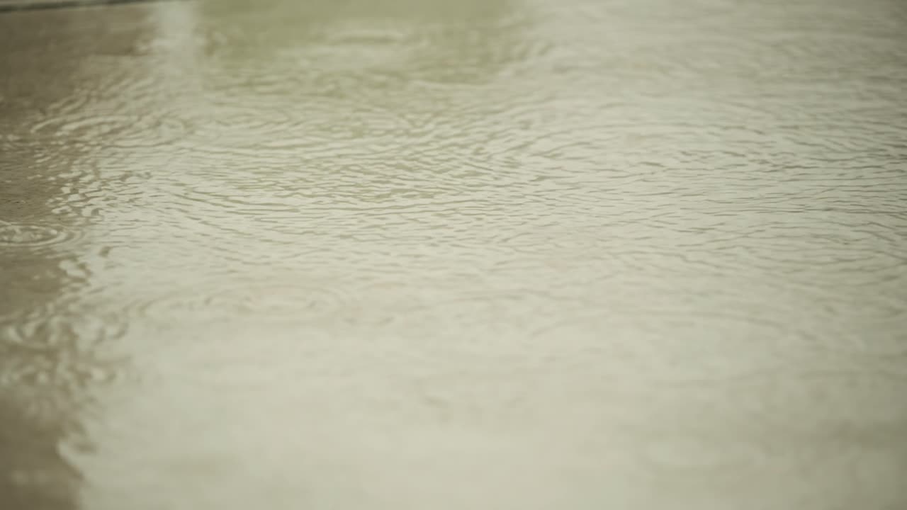 Raindrops falling on marble surface creating gentle ripples and reflections