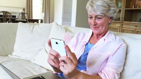 mujer mayor usando teléfono móvil en la sala de estar
