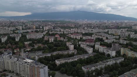 establishing aerial shot of a city full of old communist-era apartment buildings with a lot of green trees in between