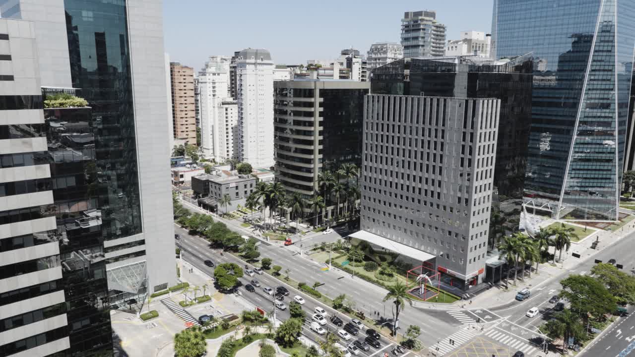 Tall office buildings line a São Paulo highway intersection and a passing airplane casts a dark shadow across the scene as the passenger jet flies by.