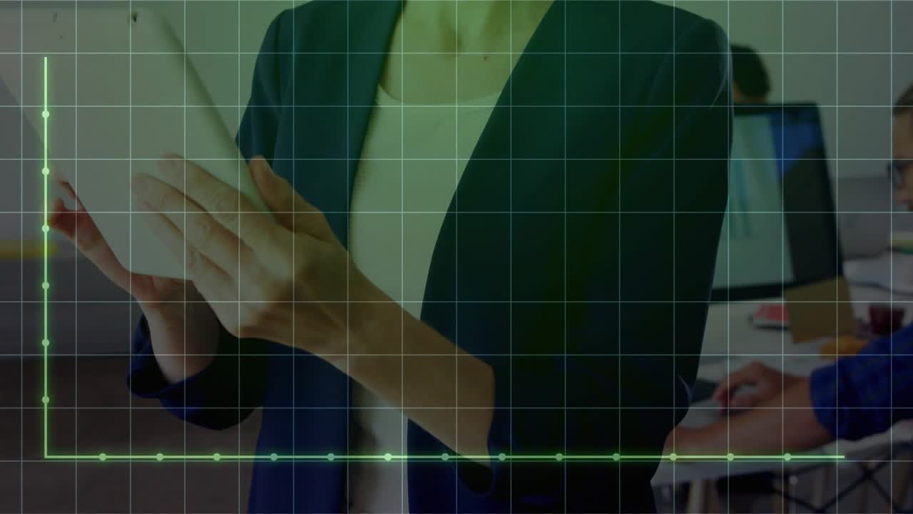 Businesswoman swiping and tapping tablet causing green graph rising spiking while coworker typing