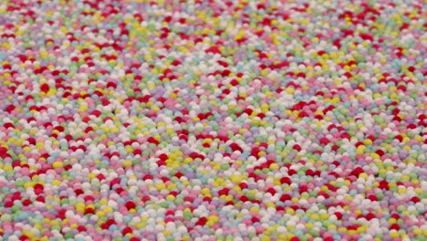 angled view of small colorful sprinkles sugar candies rotating. background.