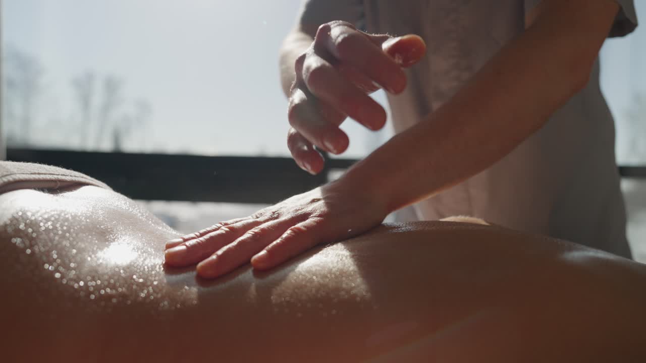 Massaggiatrice professionista che esegue un massaggio rilassante alla schiena a una donna