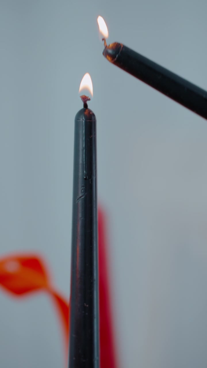 Una candela nera accesa da un'altra candela, creando un'atmosfera calda e festosa. Giorno del Ringraziamento.