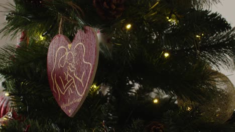 heart shaped family ornament glows on decorated christmas tree