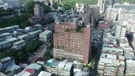 aerial drone rotating shot over taipei guandu hospital building with parking lot on both sides in beitou district, taipei, taiwan at daytime