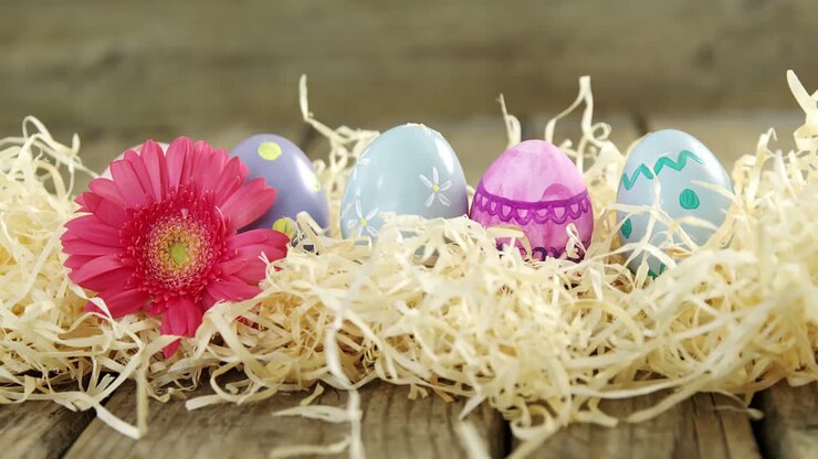 Painted Easter eggs and flower on wooden surface