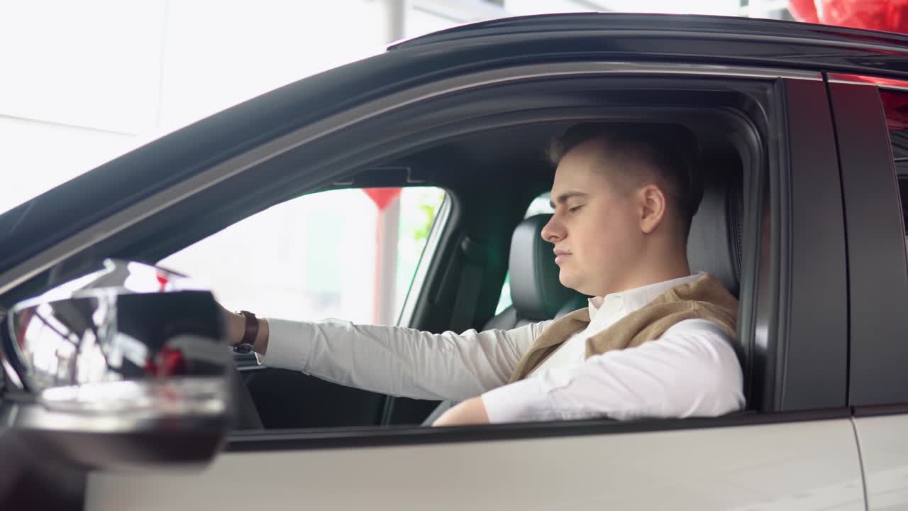 Portrait of a young confident man sitting in a new car at a car dealership. Stylish man inspects a new car at a car dealership