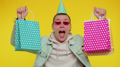 teen man showing shopping bags, advertising discounts, low prices, shopping on black friday holiday