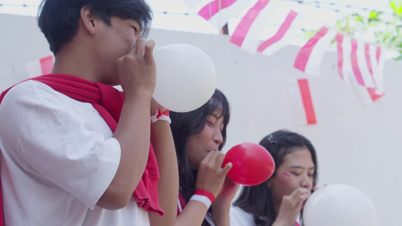 Young Asian People Having Fun Participating on Blowing Balloon Competition On Indonesian Independence Day
