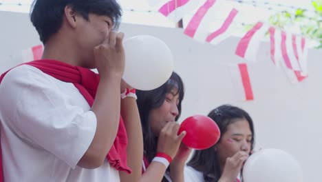 young asian people having fun participating on blowing balloon competition on indonesian independence day