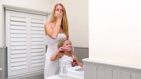 Cute-little-girl-brushing-her-teeth-with-her-mother