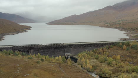 Eine-Luftaufnahme-Des-Cluanie-Staudamms-Am-Loch-Cluanie-Im-Nordwestlichen-Hochland-Von-Schottland-Am-SE-Ende-Von-Glen-Shiel-An-Einem-Bewölkten-Tag