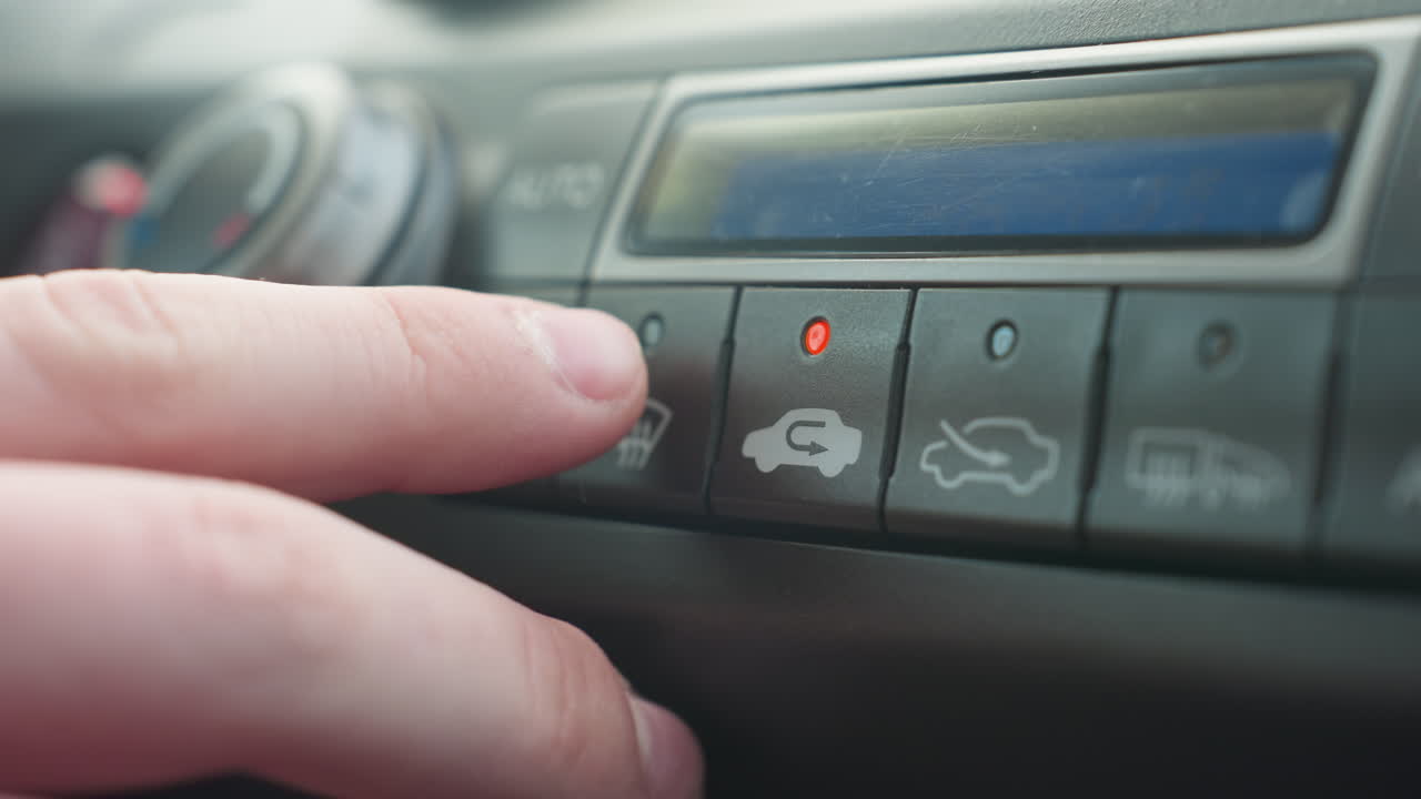 close up hand pressing ac button on car climate control panel with red indicator light and subtle lens flare adding authentic realism to cabin comfort scene interior in sunlit morning drive