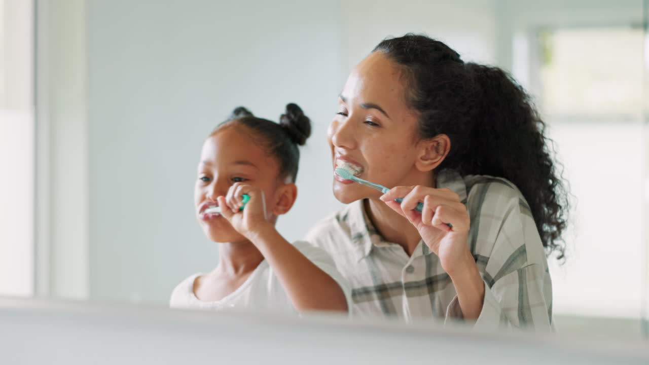 Brushing teeth, mother and daughter in mirror