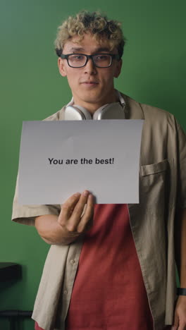 young man with braces holding a 'you are the best!' sign
