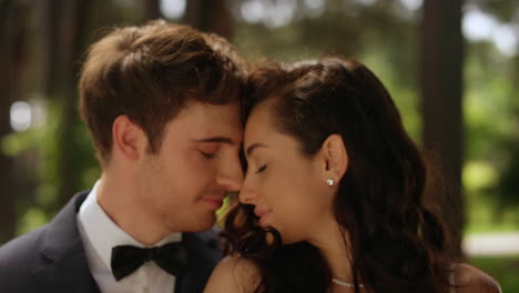 Young-man-whispering-on-ear-outdoors.-Sweet-bride-and-groom-hugging-in-park