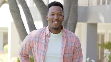 Portrait-of-happy-african-american-man-with-with-short-hair-in-garden-at-home,-slow-motion