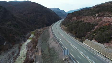 scenic view of mountain road leading through river valley with cars driving, highway in albania