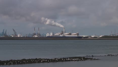 Looking-across-the-water-from-the-Hook-of-Holland-towards-factories,-chimney-docks-etc