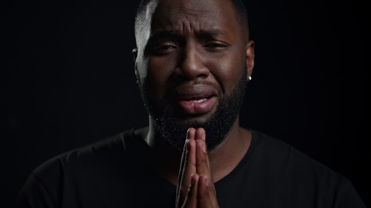 hombre afro de depresión mirando a la cámara en fondo negro. hombre llorando en el interior