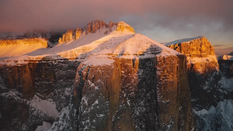 drone rises over golden snow on sella pass at dusk