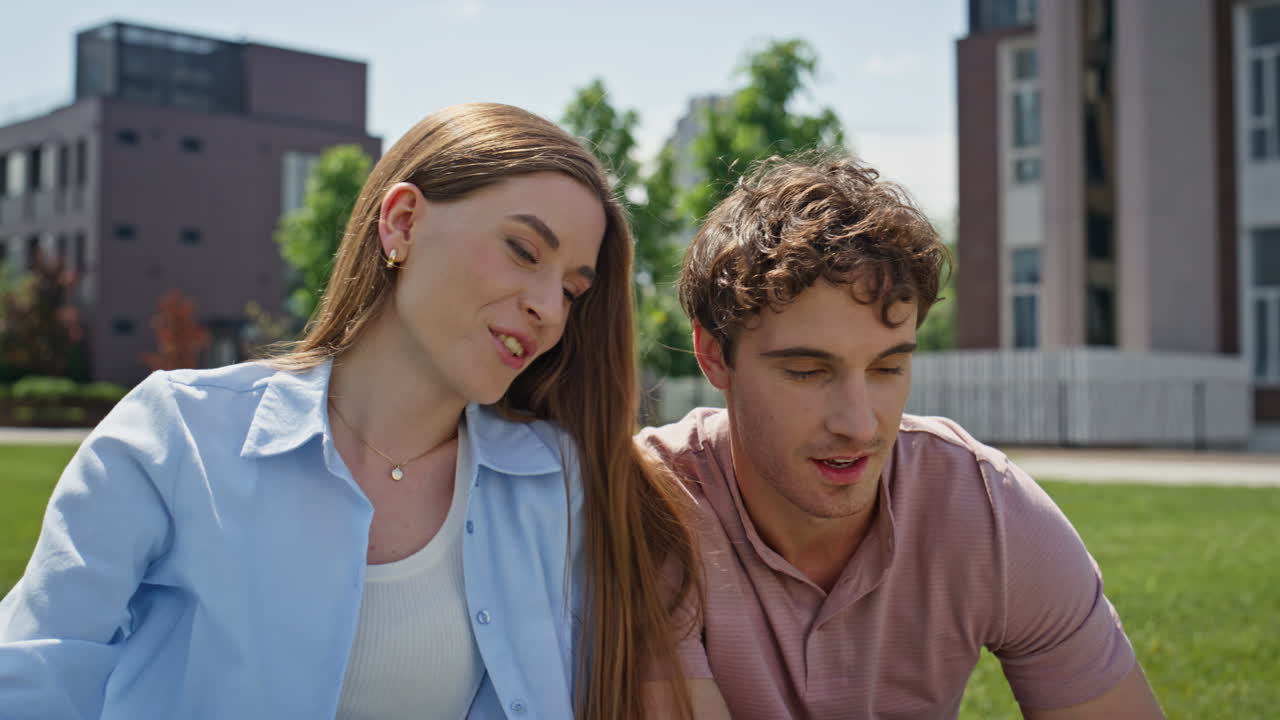 Man hand showing laptop screen to woman at outdoors study session closeup