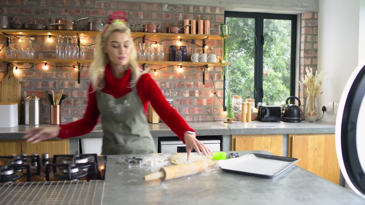 Woman wearing festive headband and apron showing star cutter dusting dough rolling cutting cookies