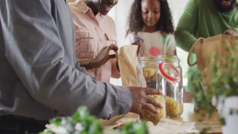 video de padres africanos americanos felices con su hija y su abuelo desempaquetando las compras de alimentos