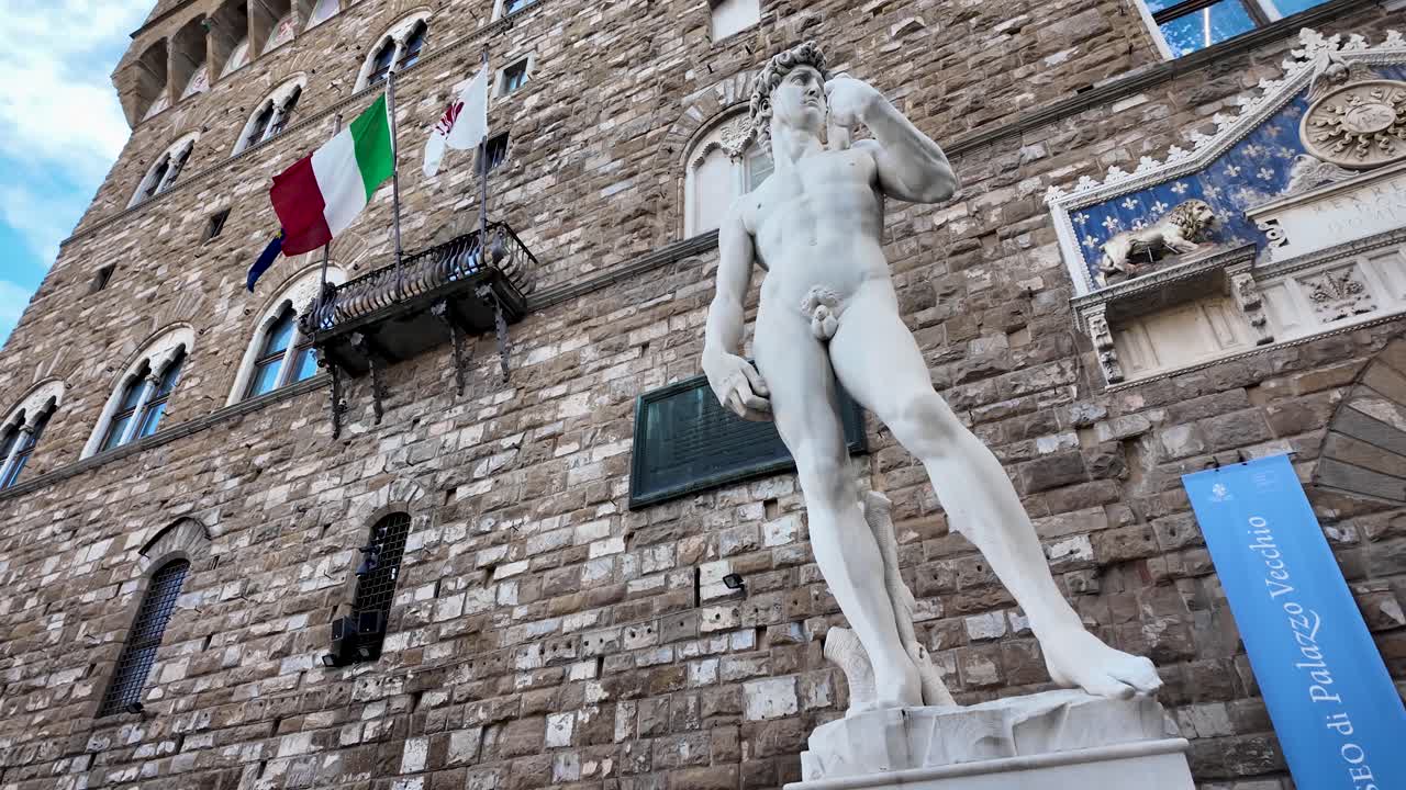 Inquadratura statica di Piazza della Signoria, con la replica del David di Michelangelo in primo piano e l'iconica facciata di Palazzo Vecchio sullo sfondo, simboli della Firenze rinascimentale, Italia.
