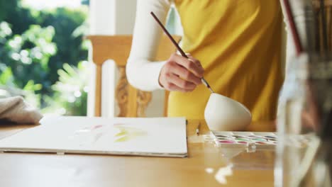 sección media de una mujer caucásica pintando en casa