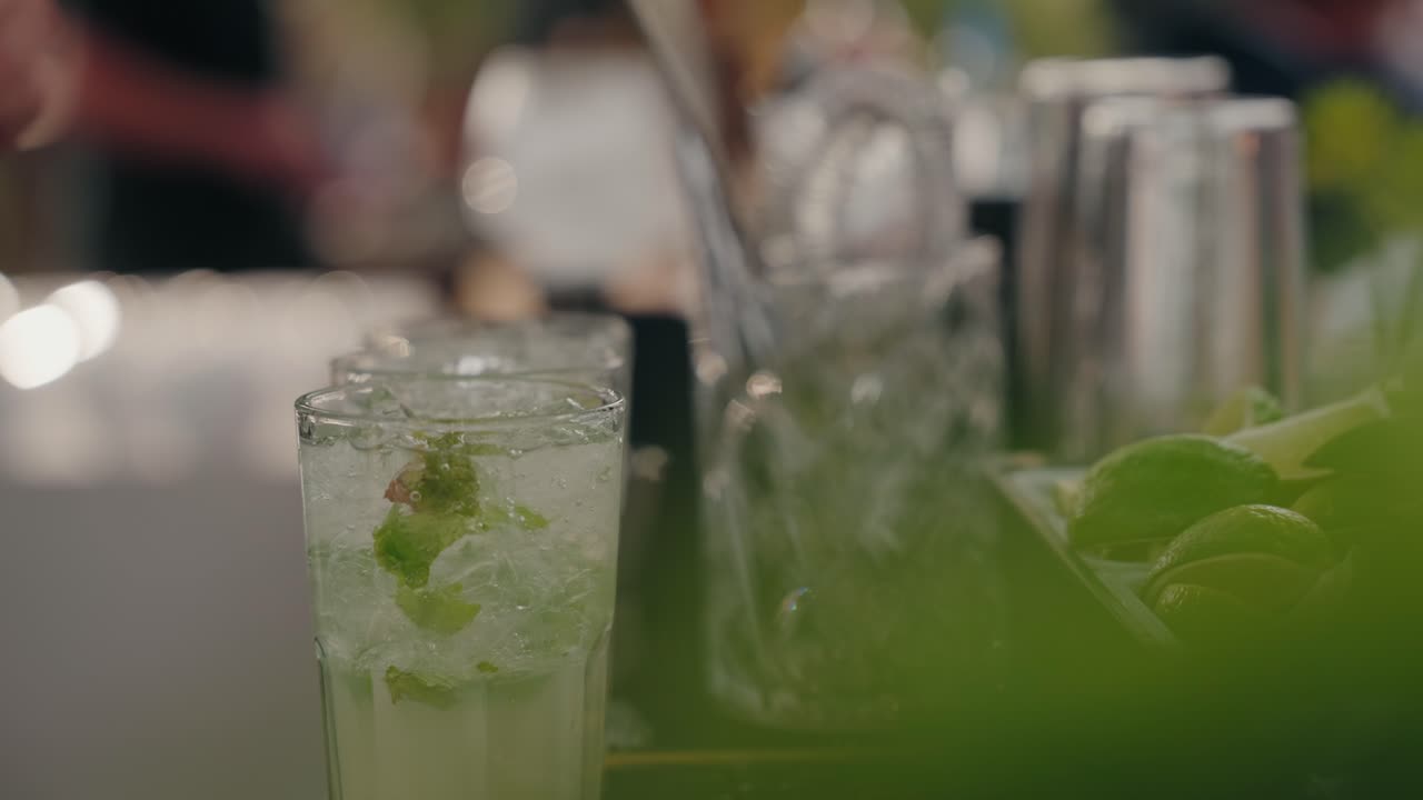 Cóctel de lima y menta preparado en un bar en un ambiente cálido al aire libre