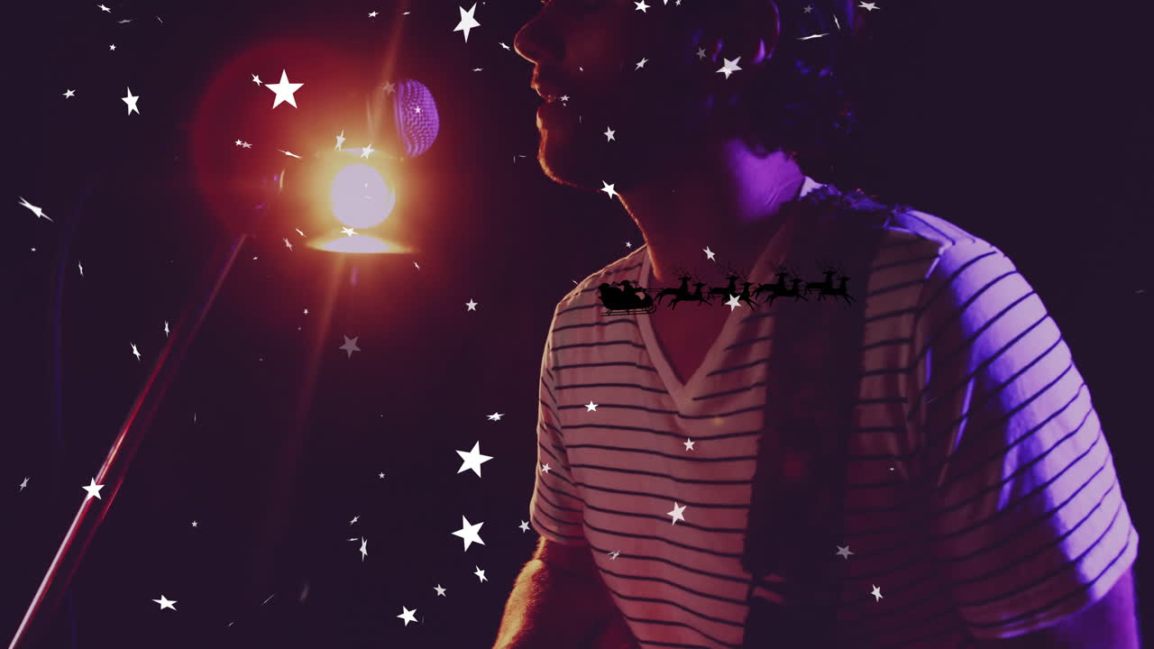 male musician playing guitar with microphone for holiday ad, with animated stars and Santa sleigh