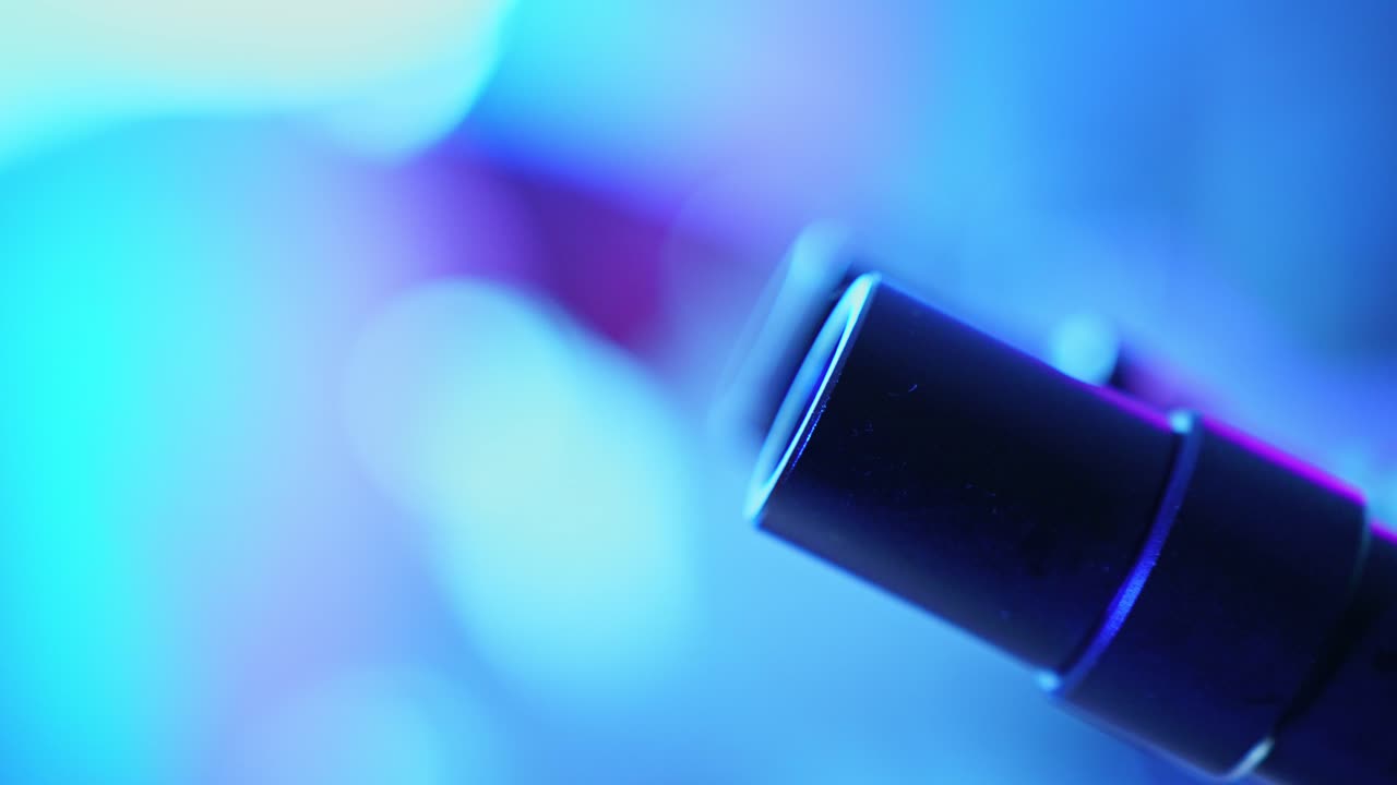 Primo piano astratto di una lente di microscopio con illuminazione blu vivace.