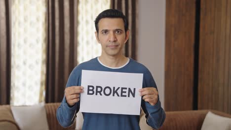 sad indian man holding broken banner