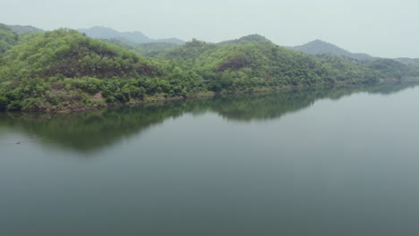 Montaña-Verde-Con-Reflejo-De-Agua-De-Río-En-La-Mañana-Desde-Un-ángulo-Plano