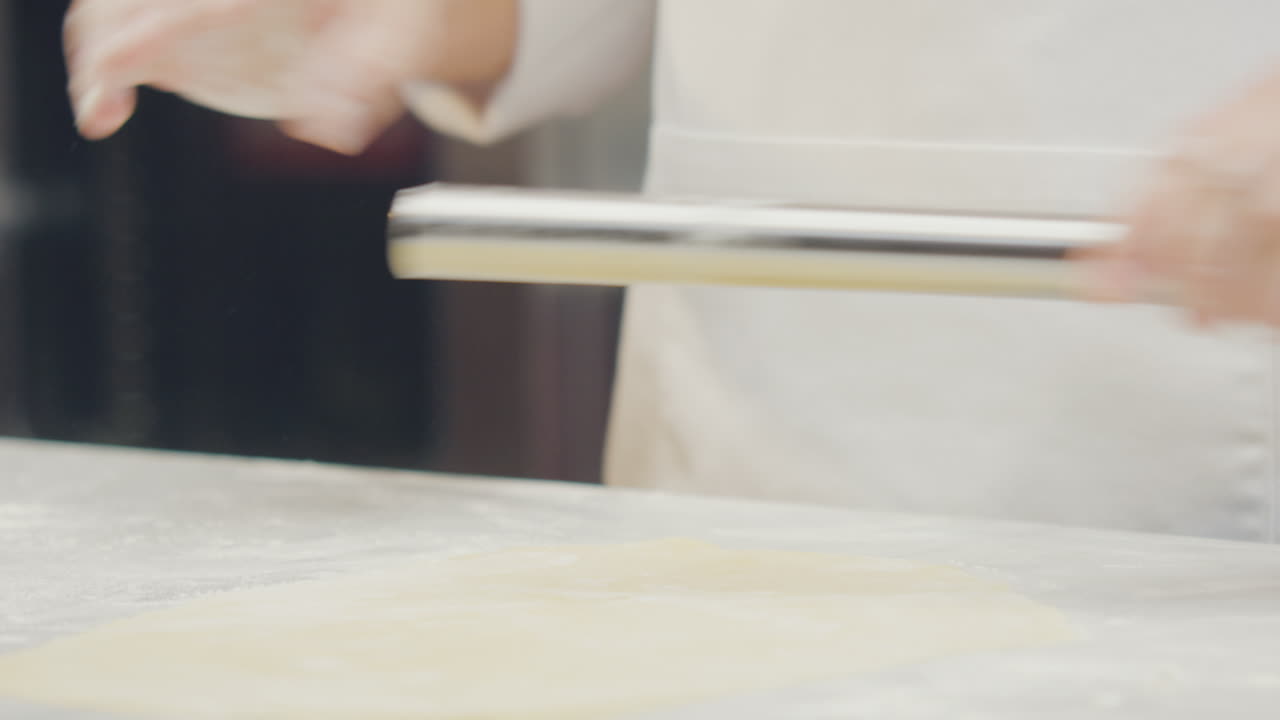 Chef's hands shaping and cutting ravioli dough using artisanal techniques in a professional kitchen