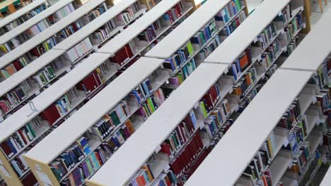 top down panning shot of rows of book shelves in a library