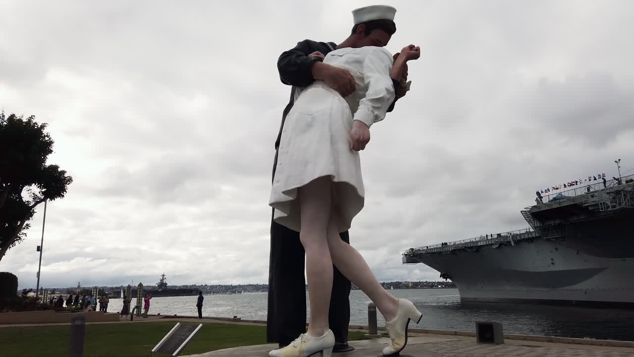 Iconic Unconditional Surrender statue of sailor and nurse embracing near the USS Midway aircraft carrier in San Diego's waterfront park