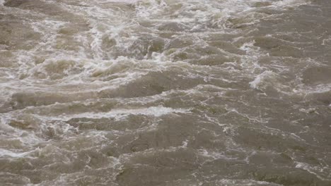 4K-Close-Up-of-Murky-Water-Raging-with-White-Water-from-a-Reservior