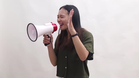young asian woman wears green t-shirt scream in megaphone announces sale hurry up to sideways isolated on white background studio portrait