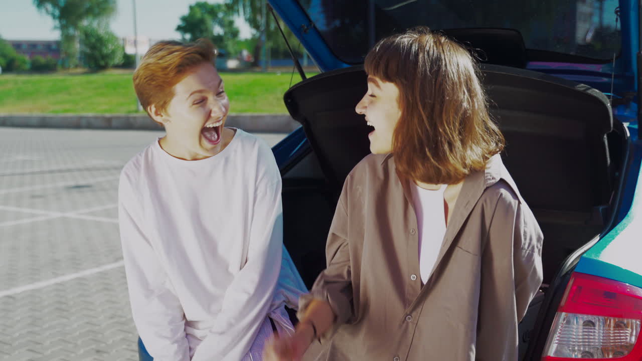 два счастливых друга разговаривают в багажнике машины.