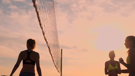 group of young girls playing beach volleyball during sunset or sunrise.